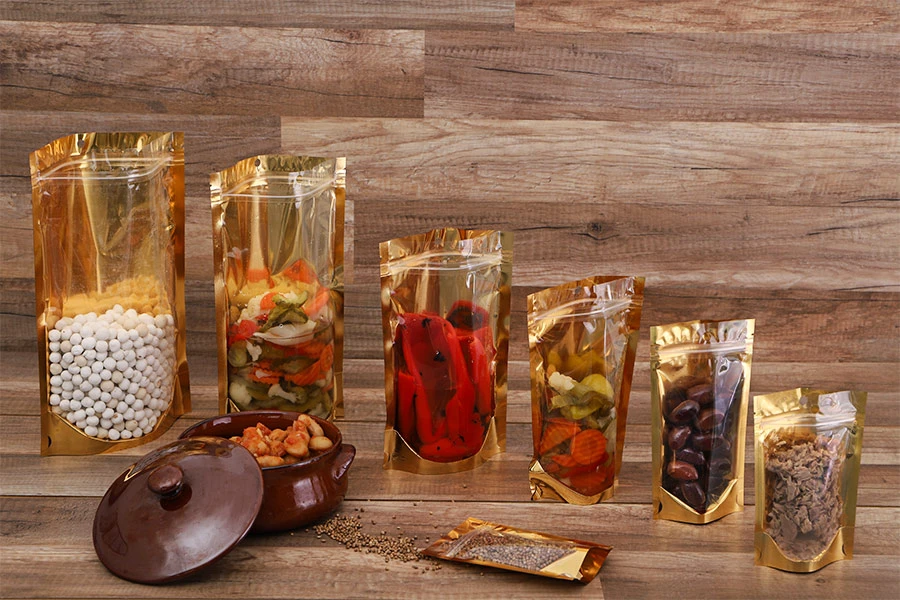 Алуминиеви торбички тип Doy Pack 130x40x205 mm със златиста задна част, прозрачна предна част с "цип" затваряне и място за термозаваряване - 100 бр. Алуминиеви торбички тип Doy Pack 130x40x205 mm със златиста задна част, прозрачна предна част с "цип" затваряне и място за термозаваряване - 100 бр.